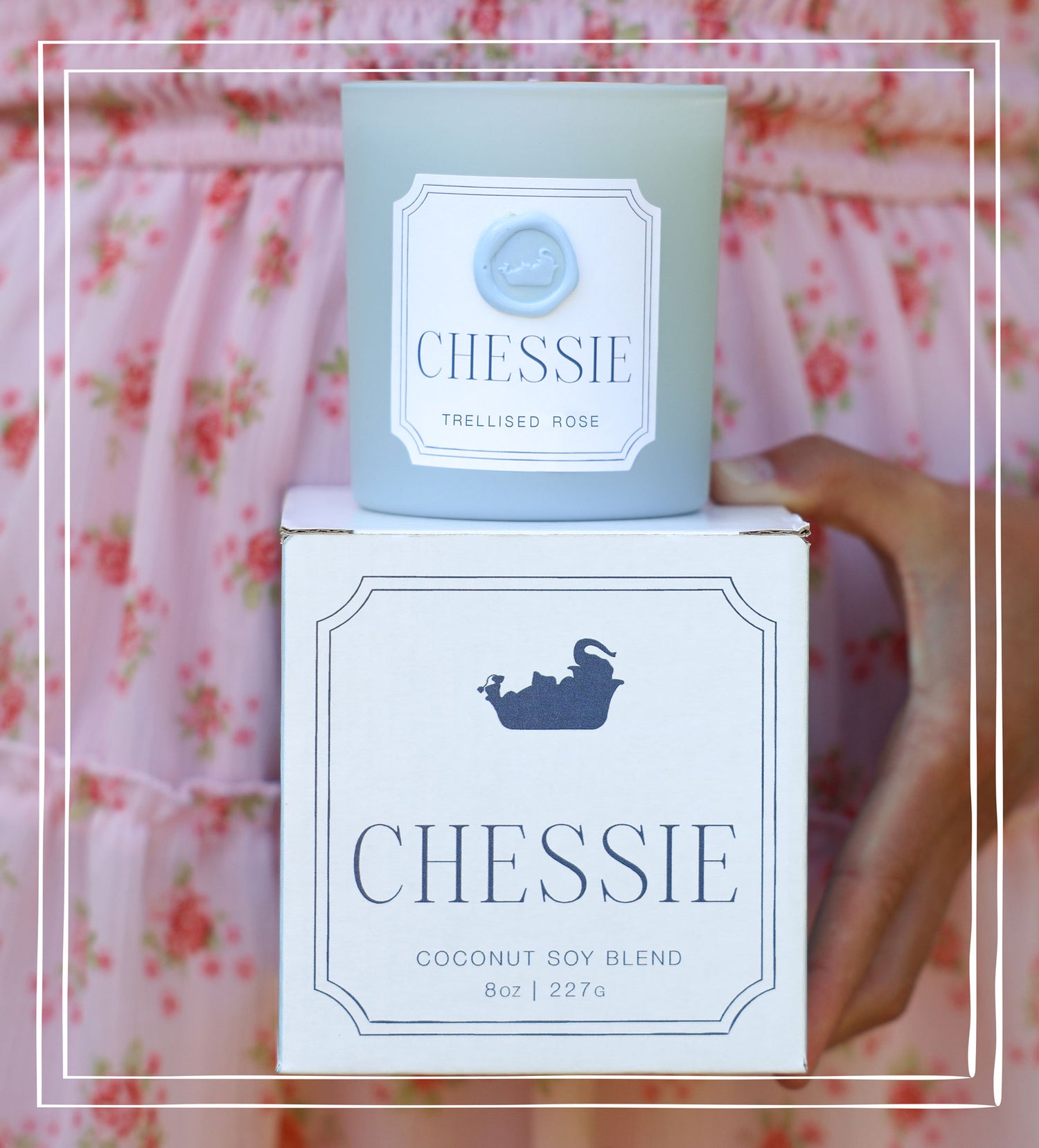 A candle jar in a pale blue glass container sits on top of its white box. The front labels read 'CHESSIE' and 'TRELLISED ROSE' on the candle and 'CHESSIE' with a dark blue elephant bathing logo on the box.